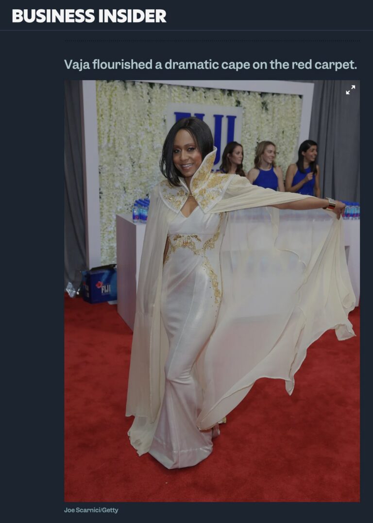 Business Insider article screenshot: Vaja in a white and gold gown with a dramatic sheer cape on the Grammy Awards red carpet.